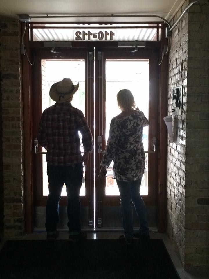 a man and a woman are standing in a doorway holding hands .