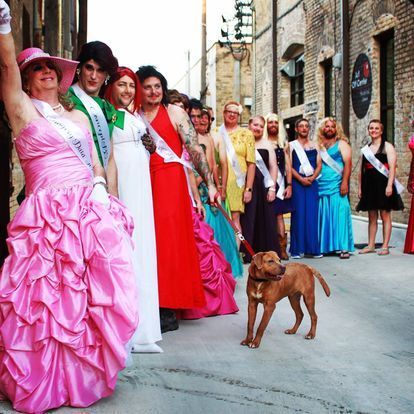 a woman in a pink dress stands in front of a group of people