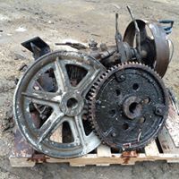 a pile of old metal gears and wheels on a wooden pallet .