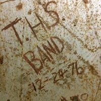 a close up of a rusty metal surface with the words ' THS band '' written on it .