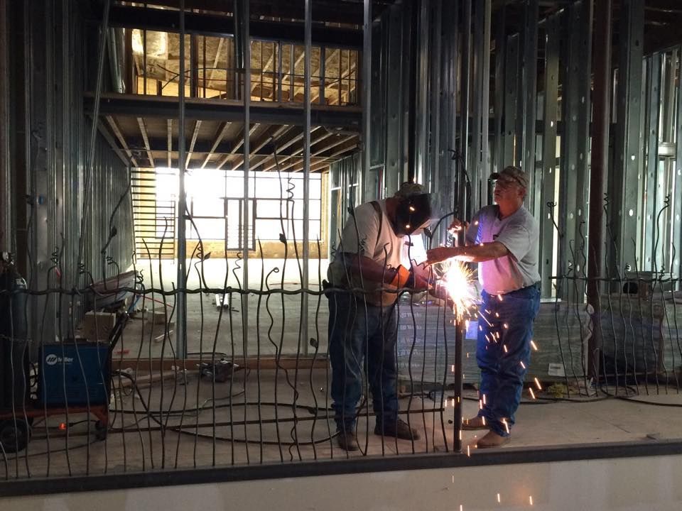 two men are welding in a building under construction .