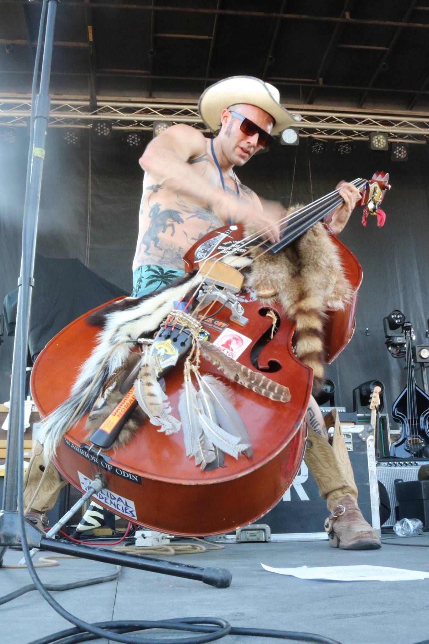 a man in a cowboy hat is playing a double bass
