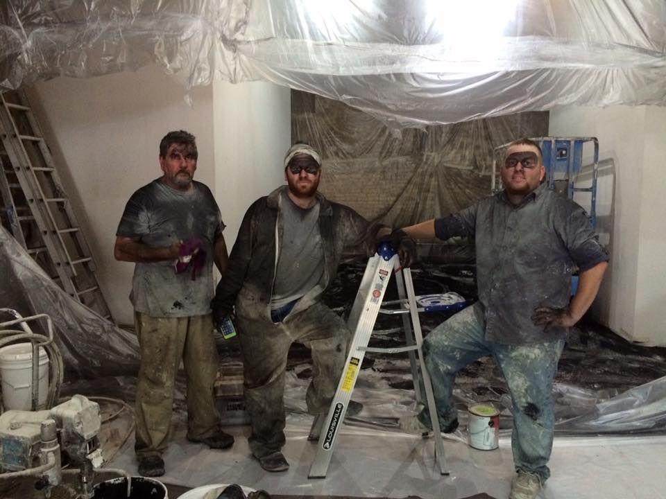 three men standing next to each other in a room with a ladder
