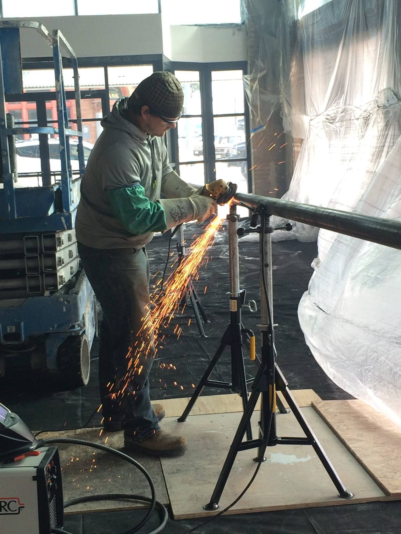 a man is cutting a metal pipe with a grinder