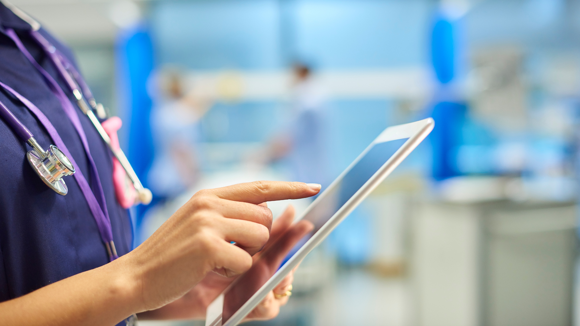 A nurse is using a tablet computer in a hospital room.