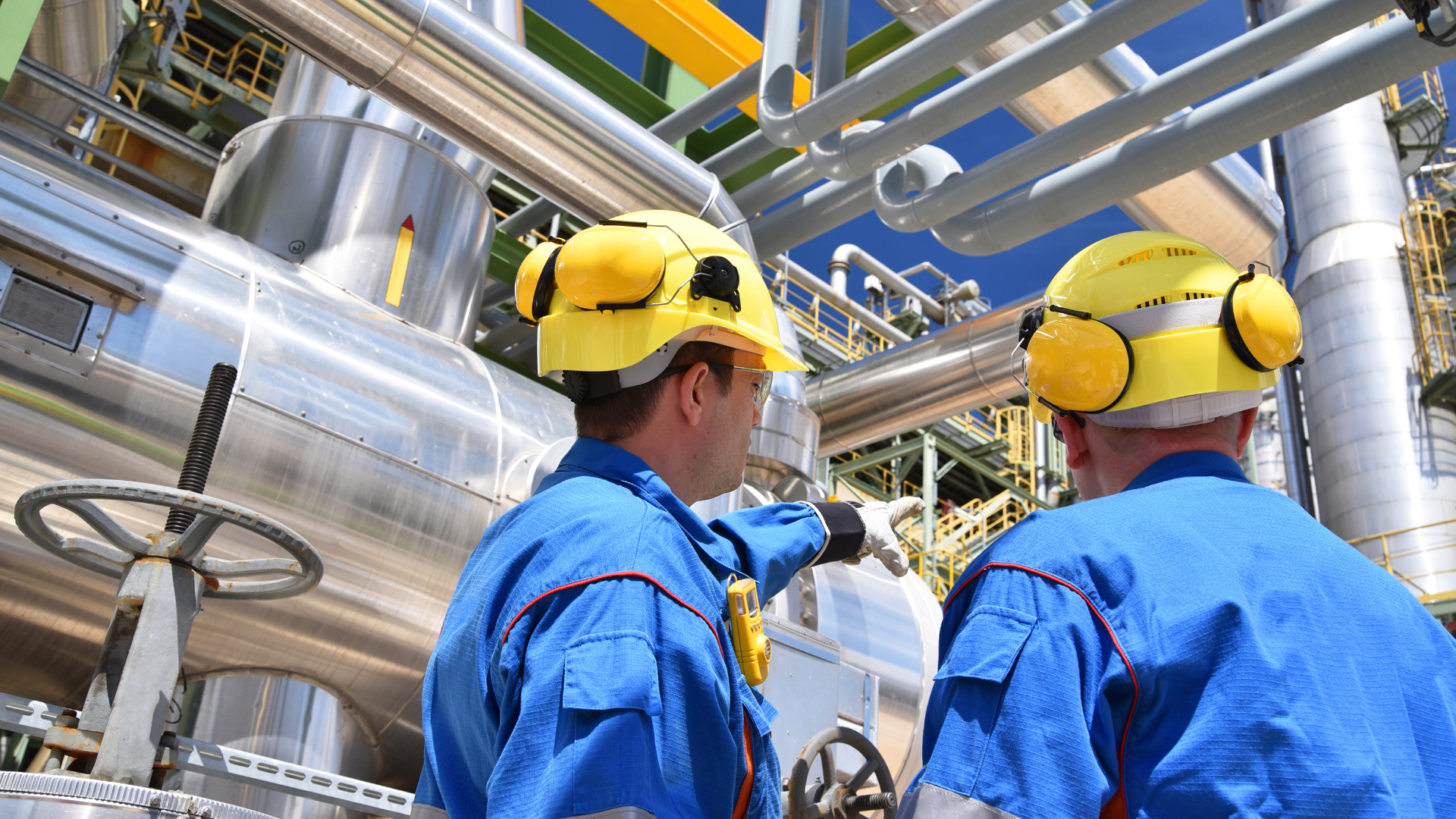 Two men wearing hard hats are working in a factory.