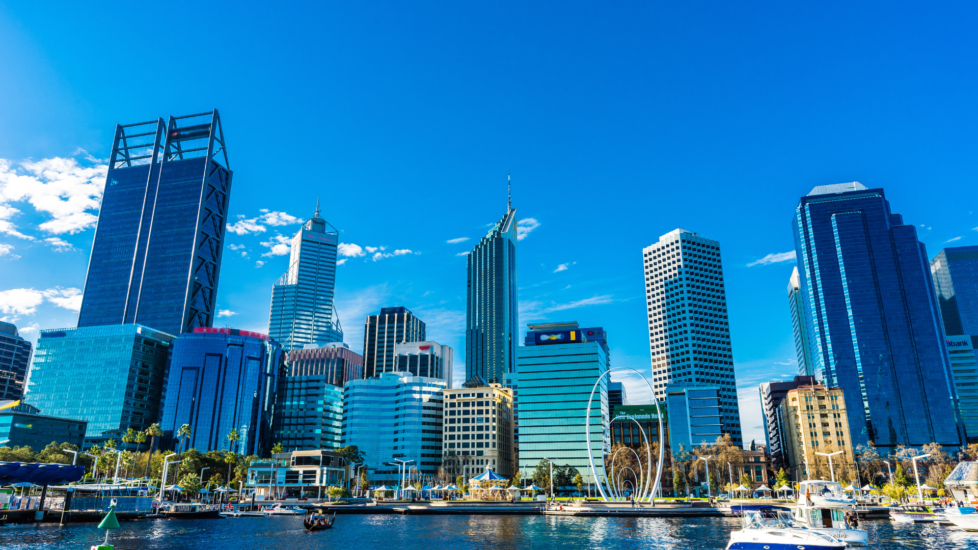 A city skyline with a boat in the foreground and a body of water in the background.