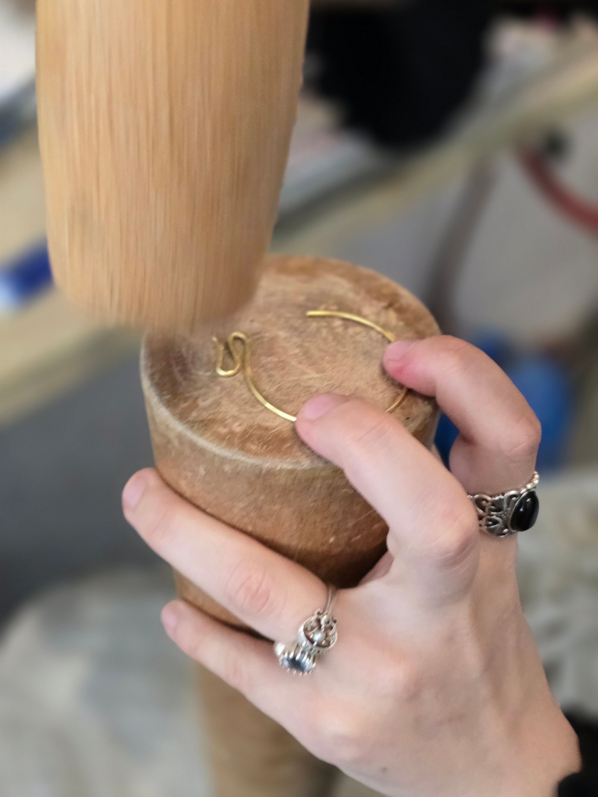 雙手用木槌和圓柱形木模塑造金飾。