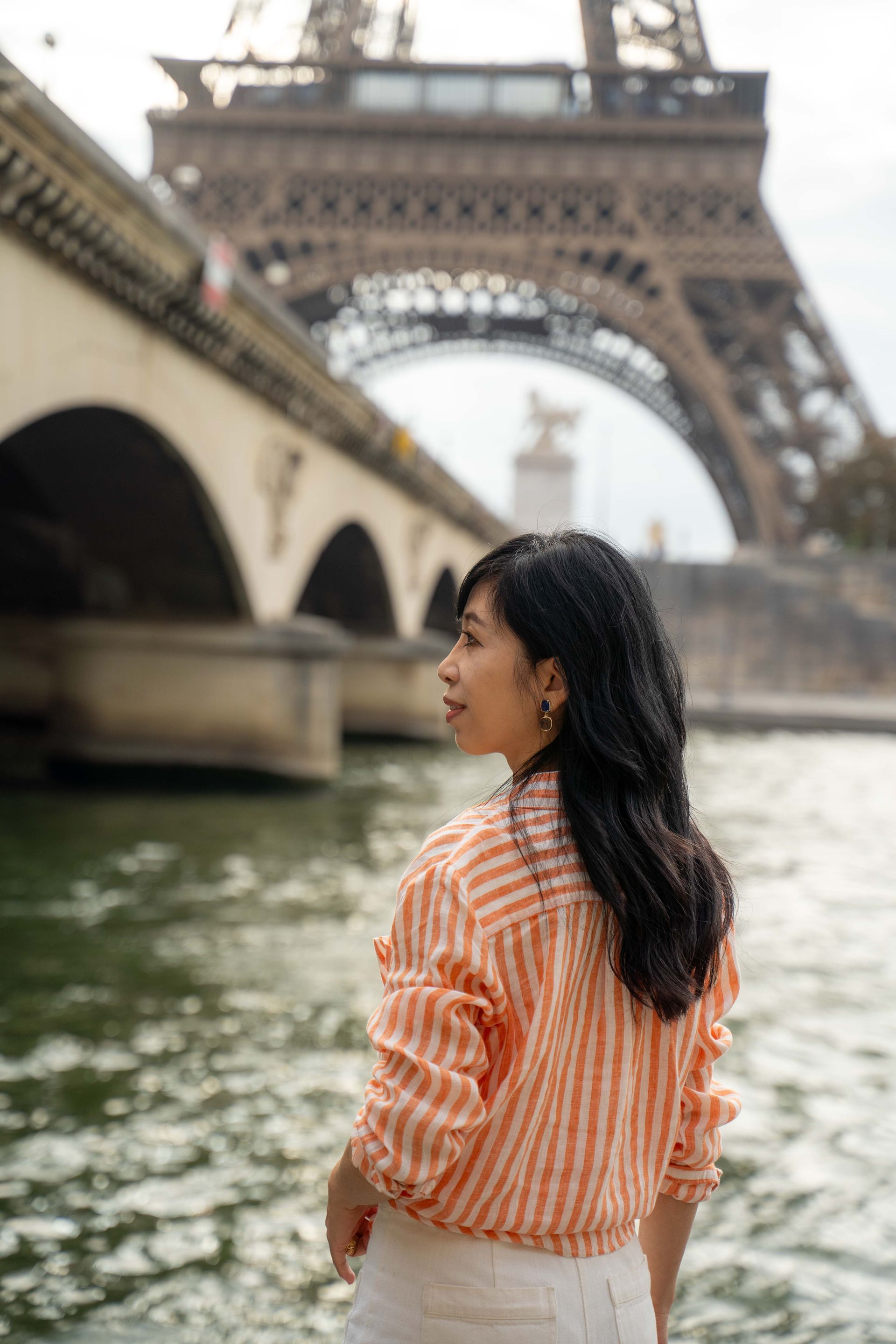 身穿橘色條紋襯衫的女子正在巴黎眺望艾菲爾鐵塔。