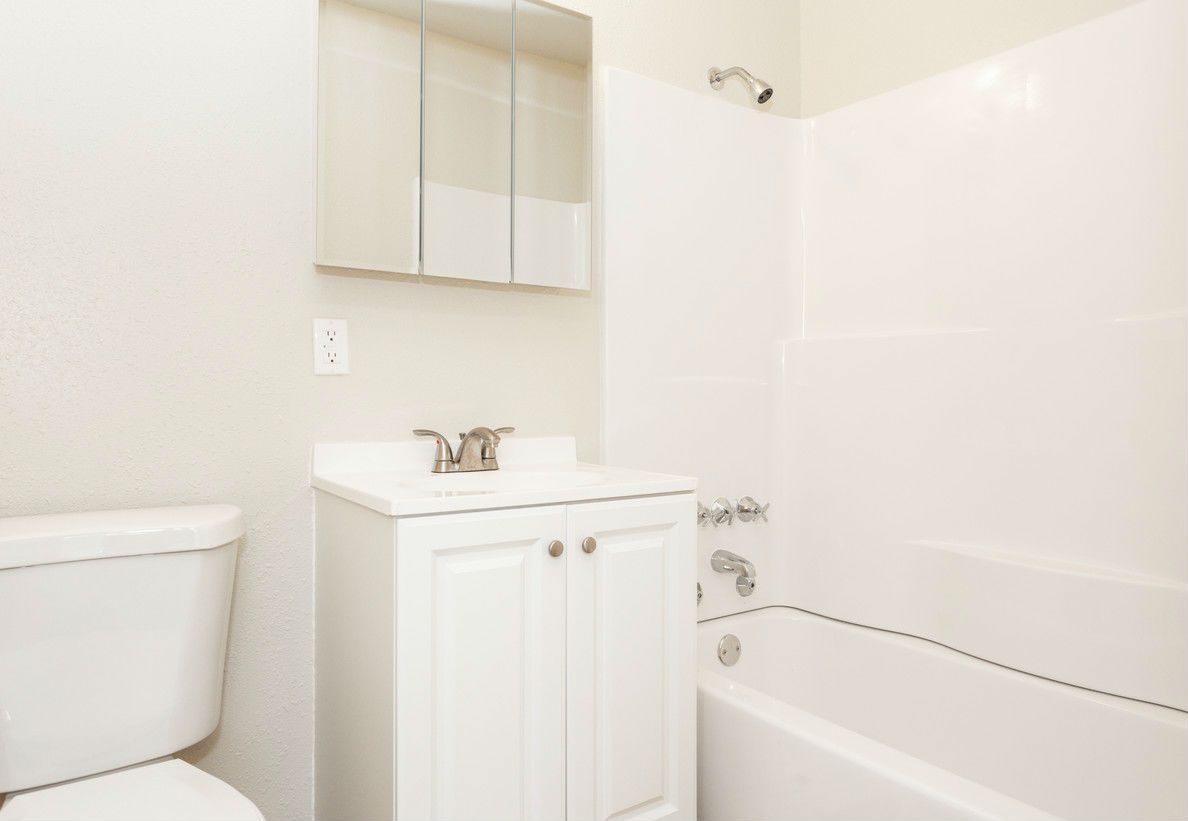 White bathroom with toilet, vanity, and bathtub.