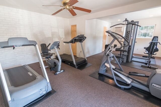 Gym with treadmills, elliptical, stationary bikes, and weight machine on a carpeted floor.