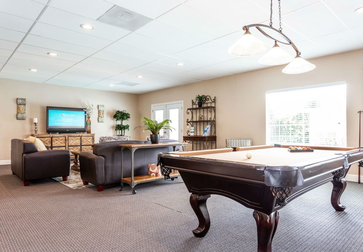 Pool table in a recreation room with seating, TV, and a decorative chandelier.