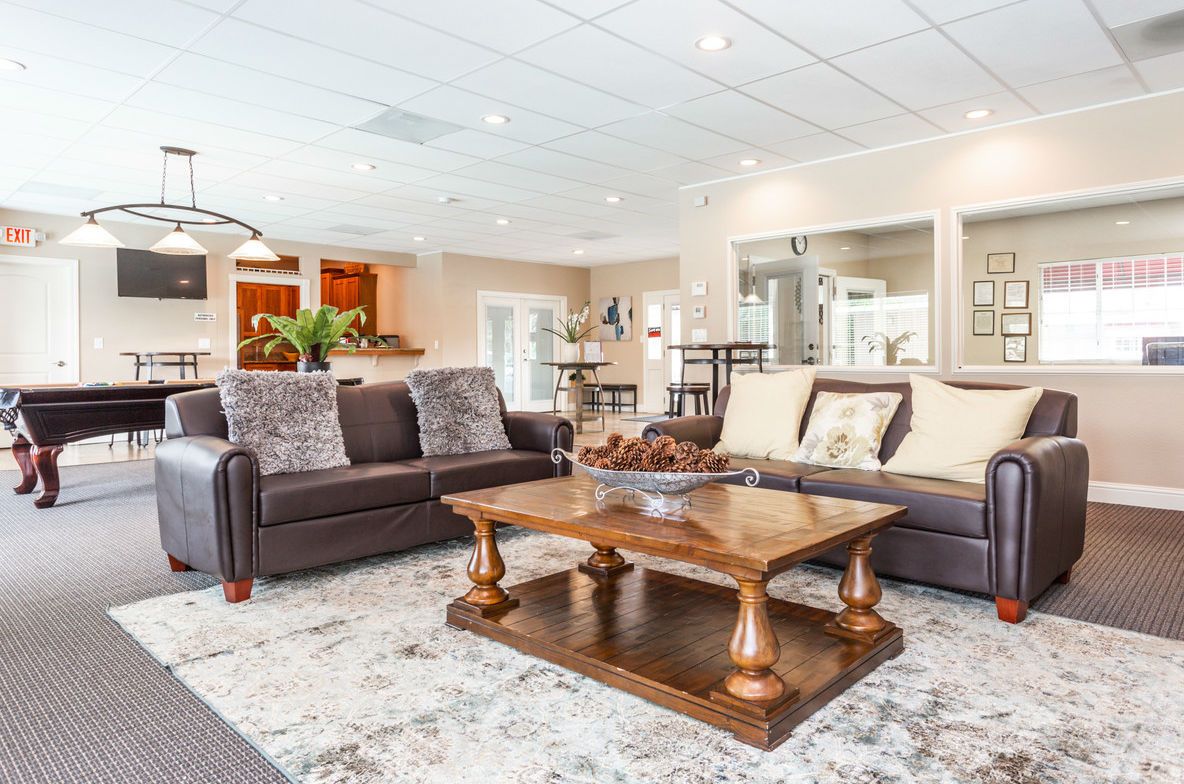 Spacious lounge with brown leather sofas, coffee table, and a pool table in the background.