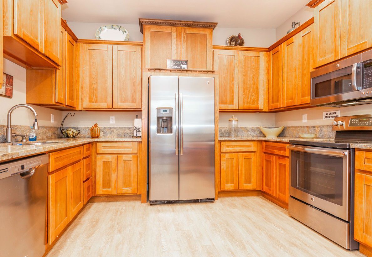 A kitchen with light wood cabinets, stainless steel appliances, and granite countertops.