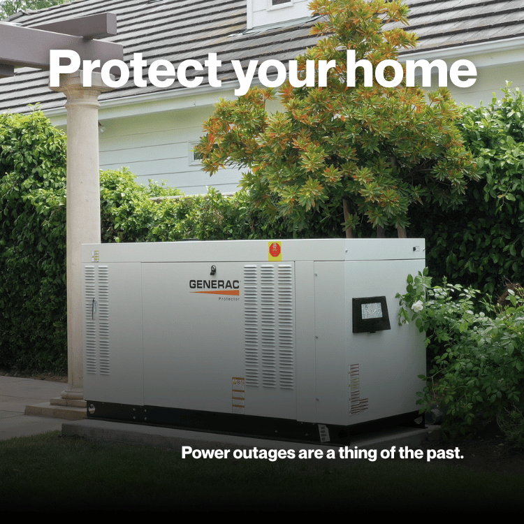 White Generac generator next to a red barn with firewood. Gravel ground.