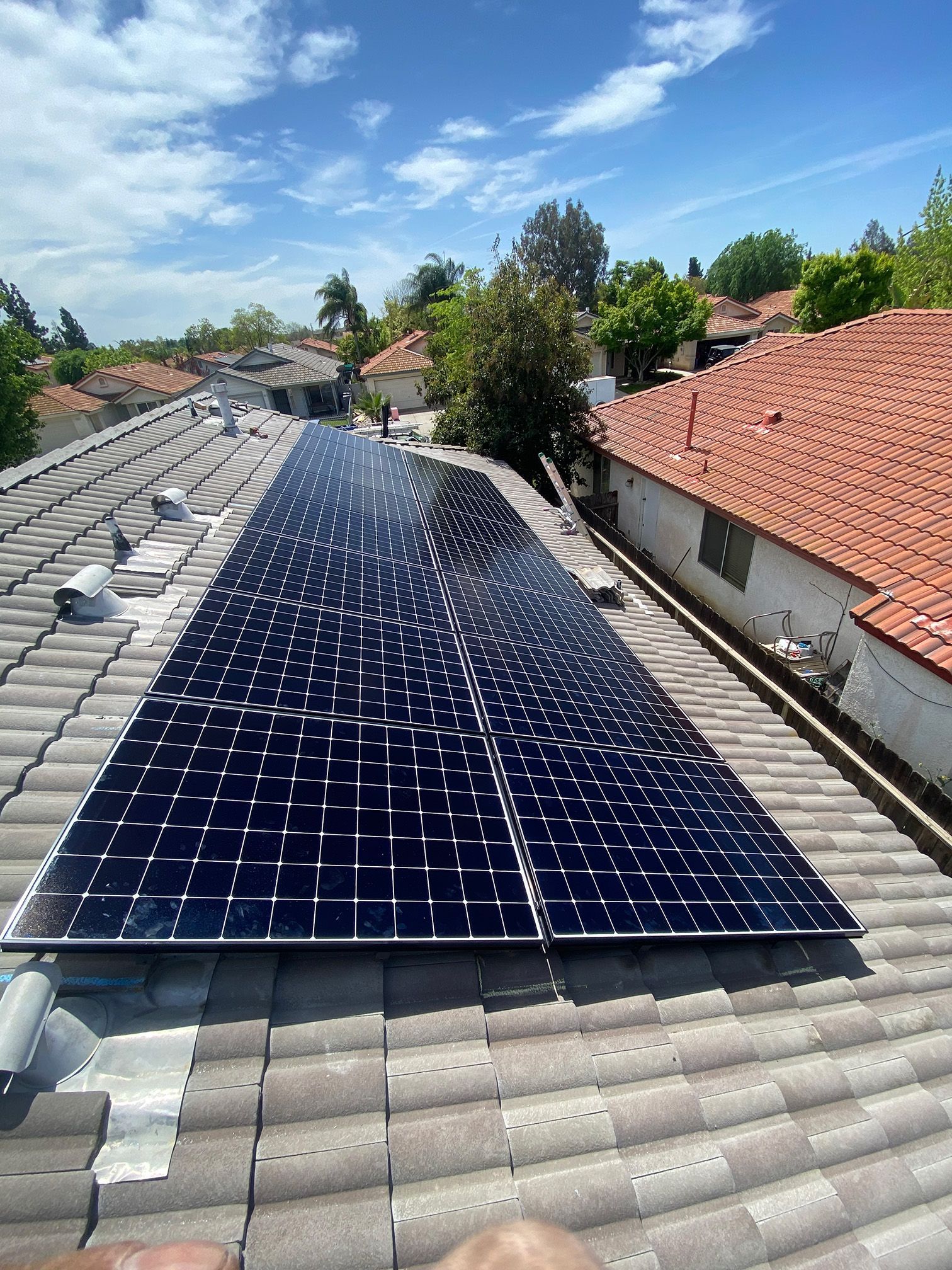 Solar panels on a red tile roof with a blue sky background.