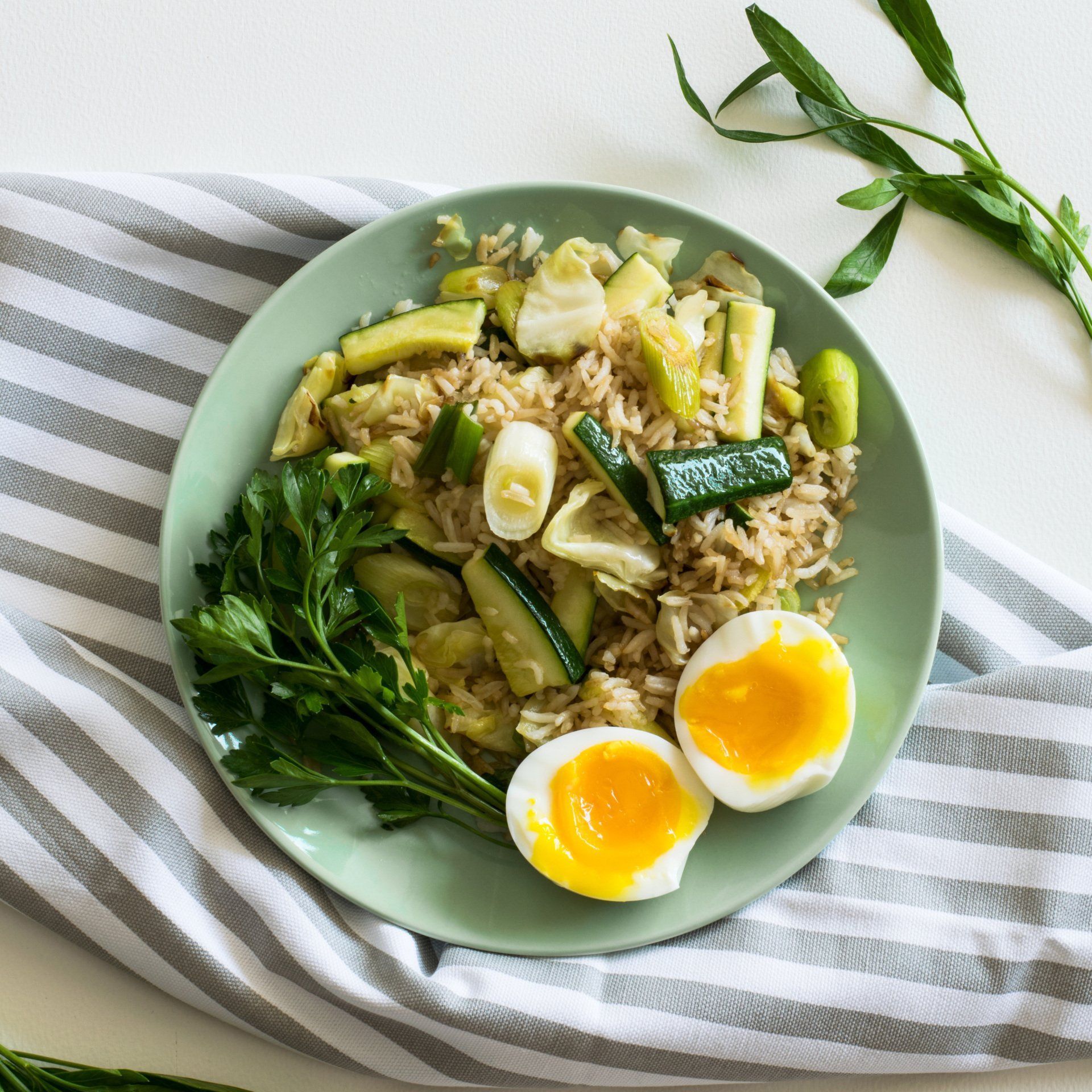 A green plate topped with rice eggs and vegetables