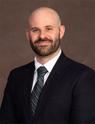 A smiling doctor in a lab coat with a stethoscope around his neck.