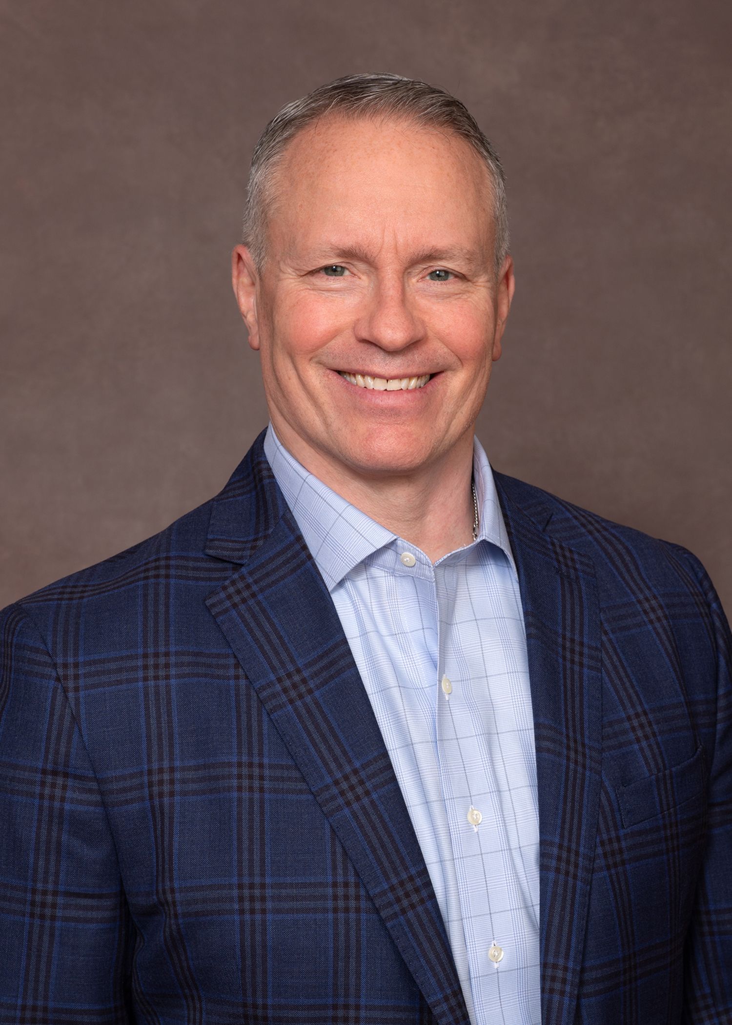 A smiling doctor in a lab coat with a stethoscope around his neck.