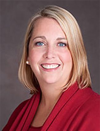 A smiling doctor in a lab coat with a stethoscope around his neck.