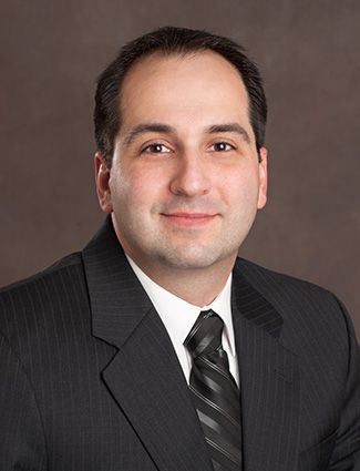A smiling doctor in a lab coat with a stethoscope around his neck.