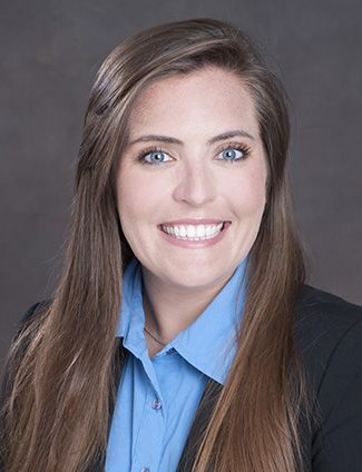 A smiling doctor in a lab coat with a stethoscope around his neck.