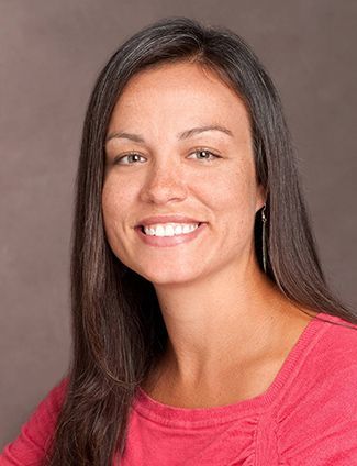A smiling doctor in a lab coat with a stethoscope around his neck.
