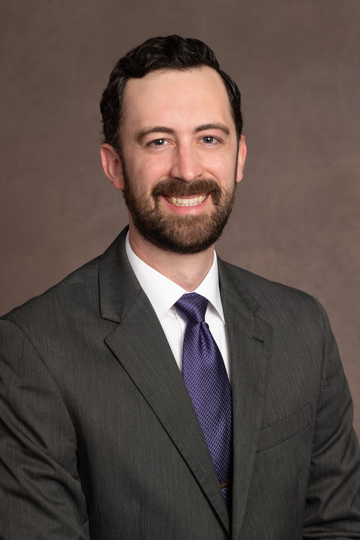 A smiling doctor in a lab coat with a stethoscope around his neck.