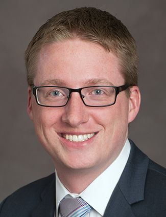 A smiling doctor in a lab coat with a stethoscope around his neck.