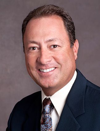 A smiling doctor in a lab coat with a stethoscope around his neck.