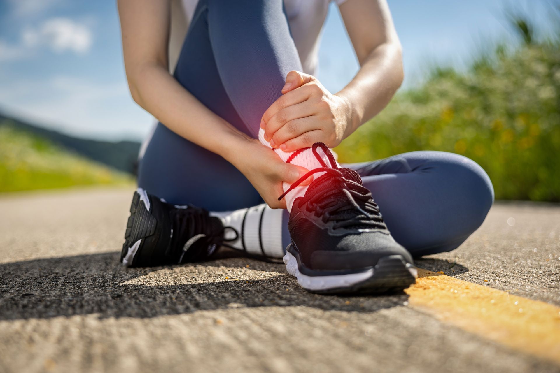 Woman sitting, holding ankle in pain; red highlight indicating injury on shoe and leg.