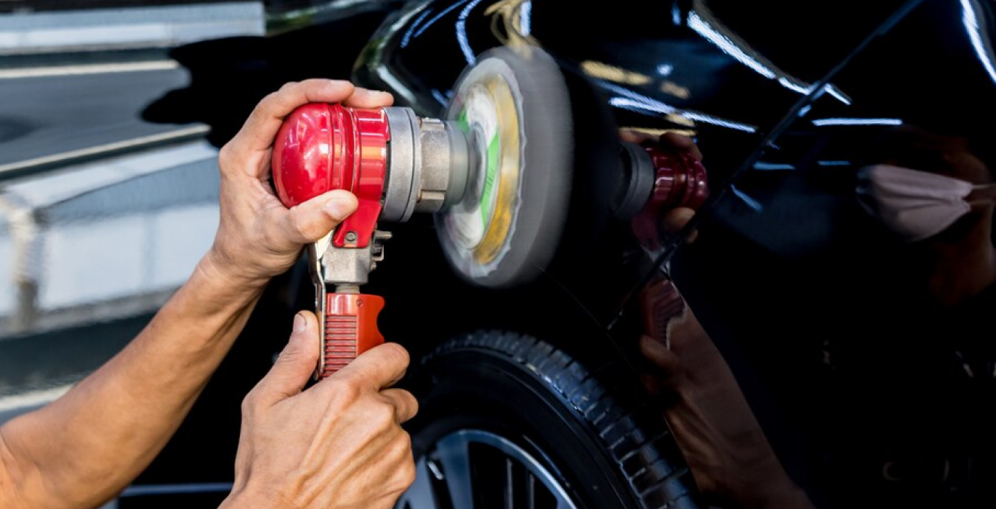 A man is polishing a black car detailed by That's Clean in Frederick MD