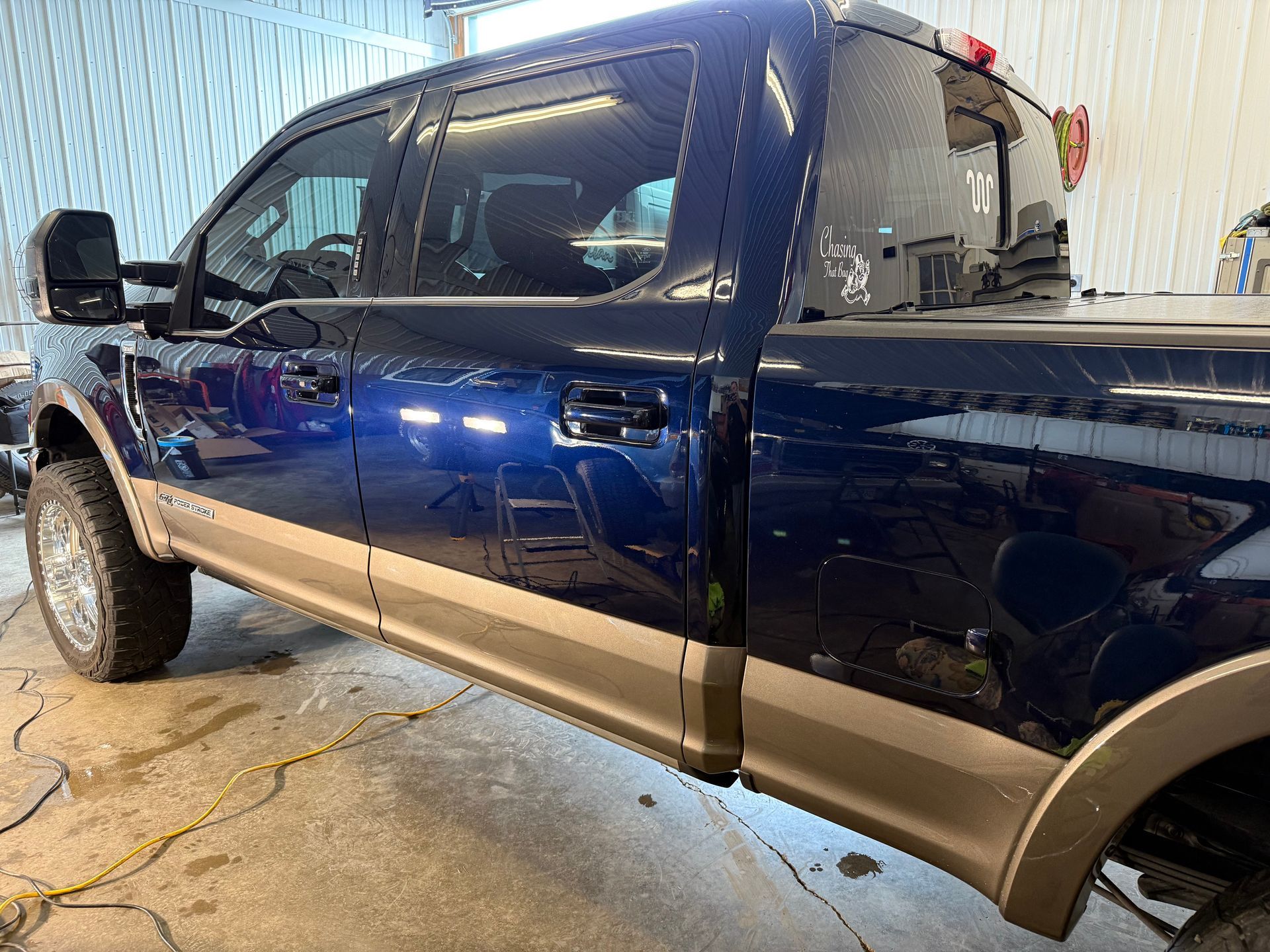A blue pickup truck is parked in a garage.