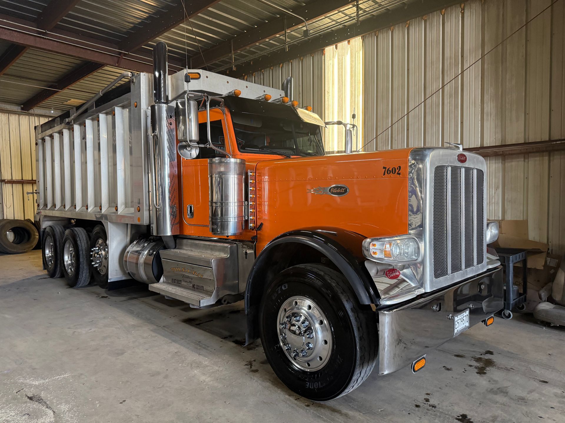 A large orange dump truck is parked in a warehouse.