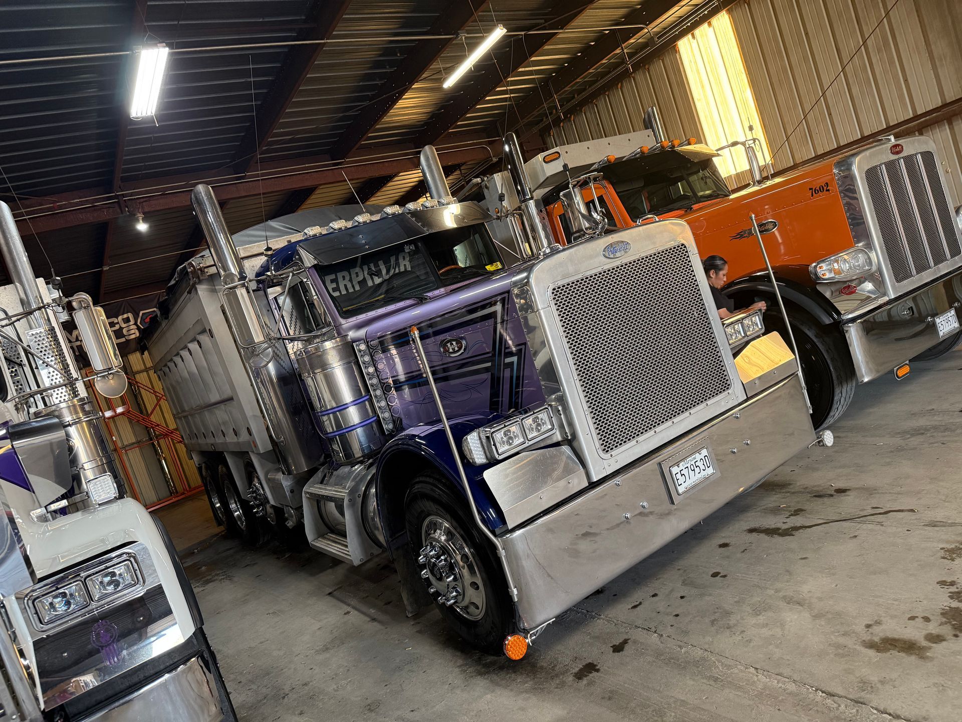 Two semi trucks are parked in a garage.