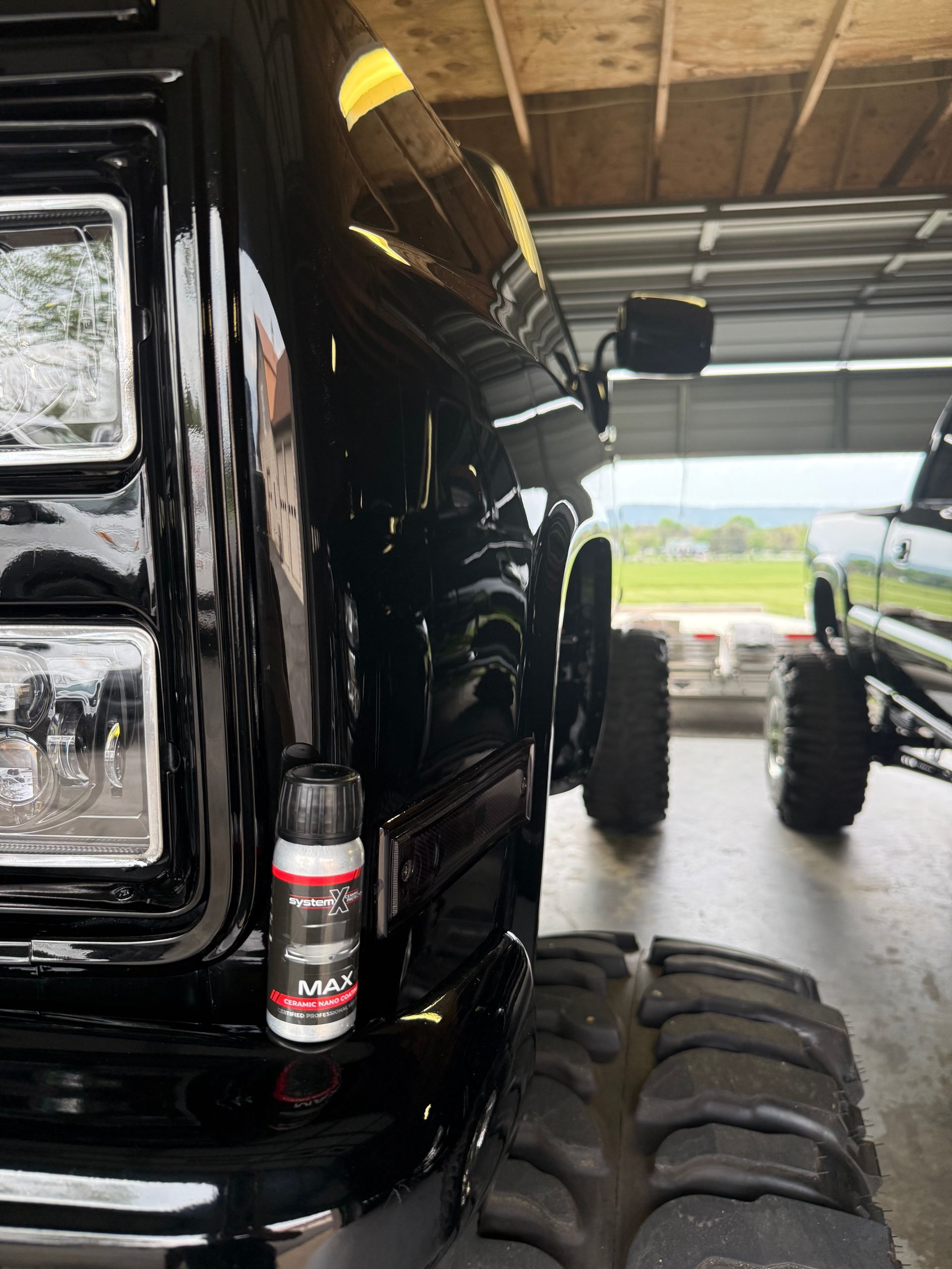 A black truck is parked in a garage next to a green truck.