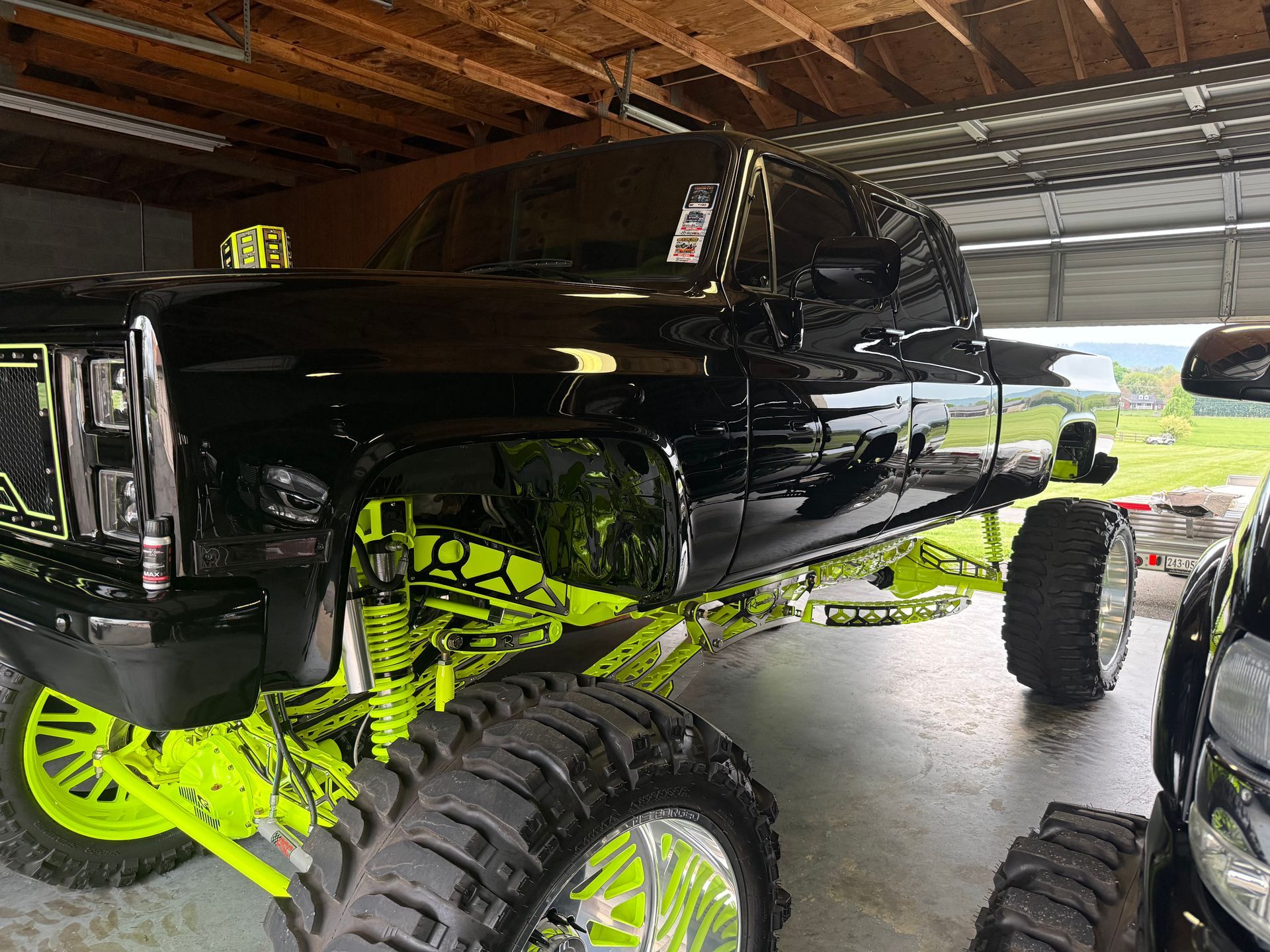 A black truck with neon green wheels is parked in a garage.