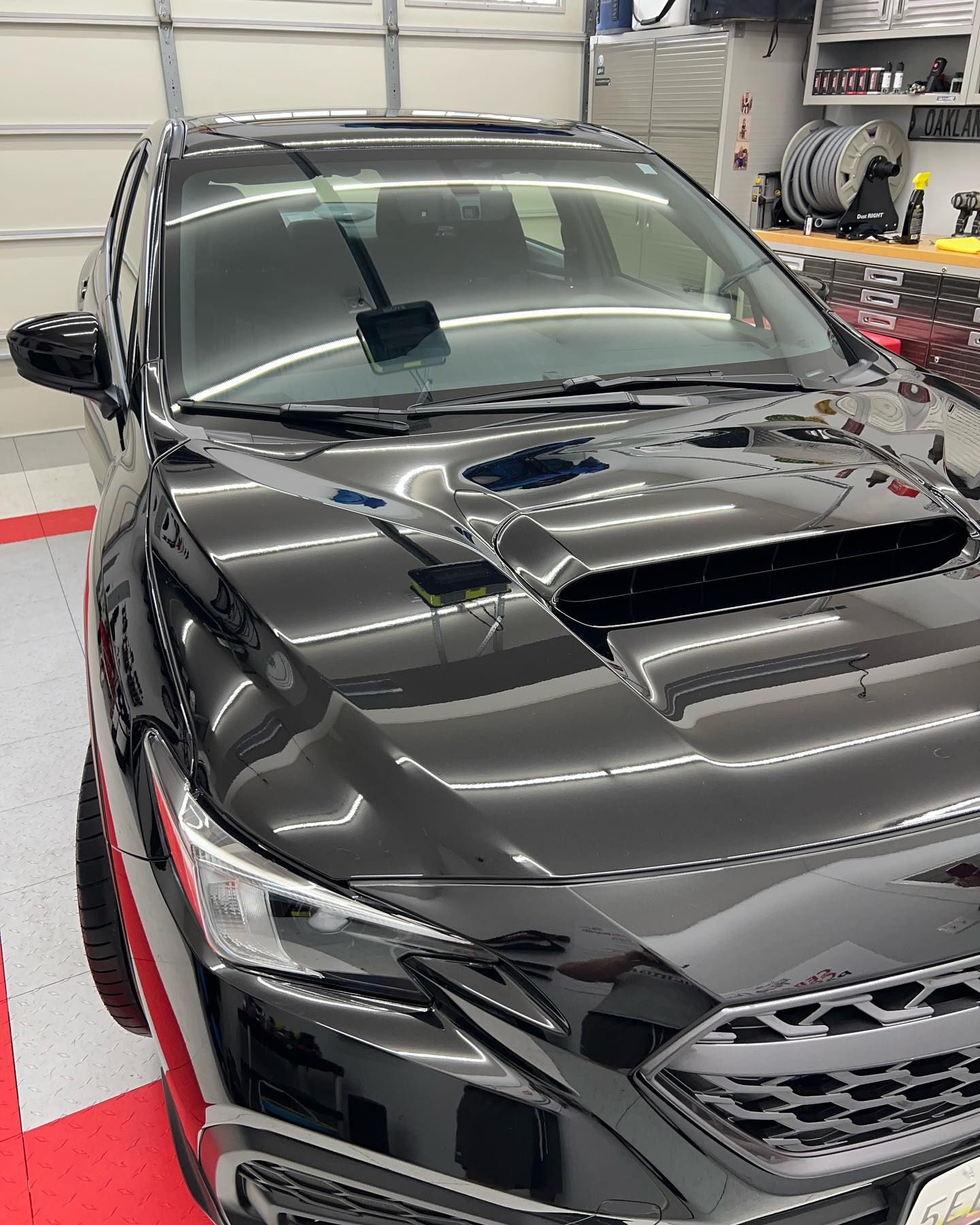 A black subaru wrx sti is parked in a garage.