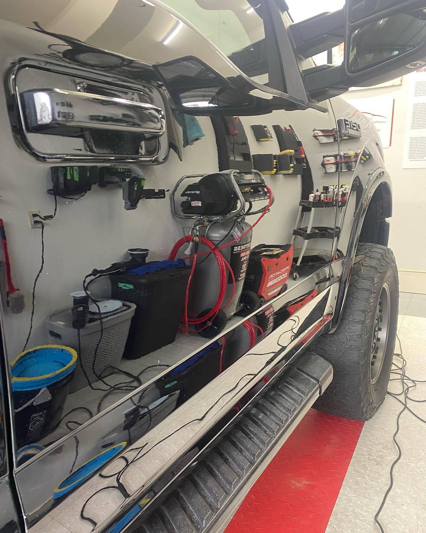 A truck is parked in a garage with a lot of tools on the side.