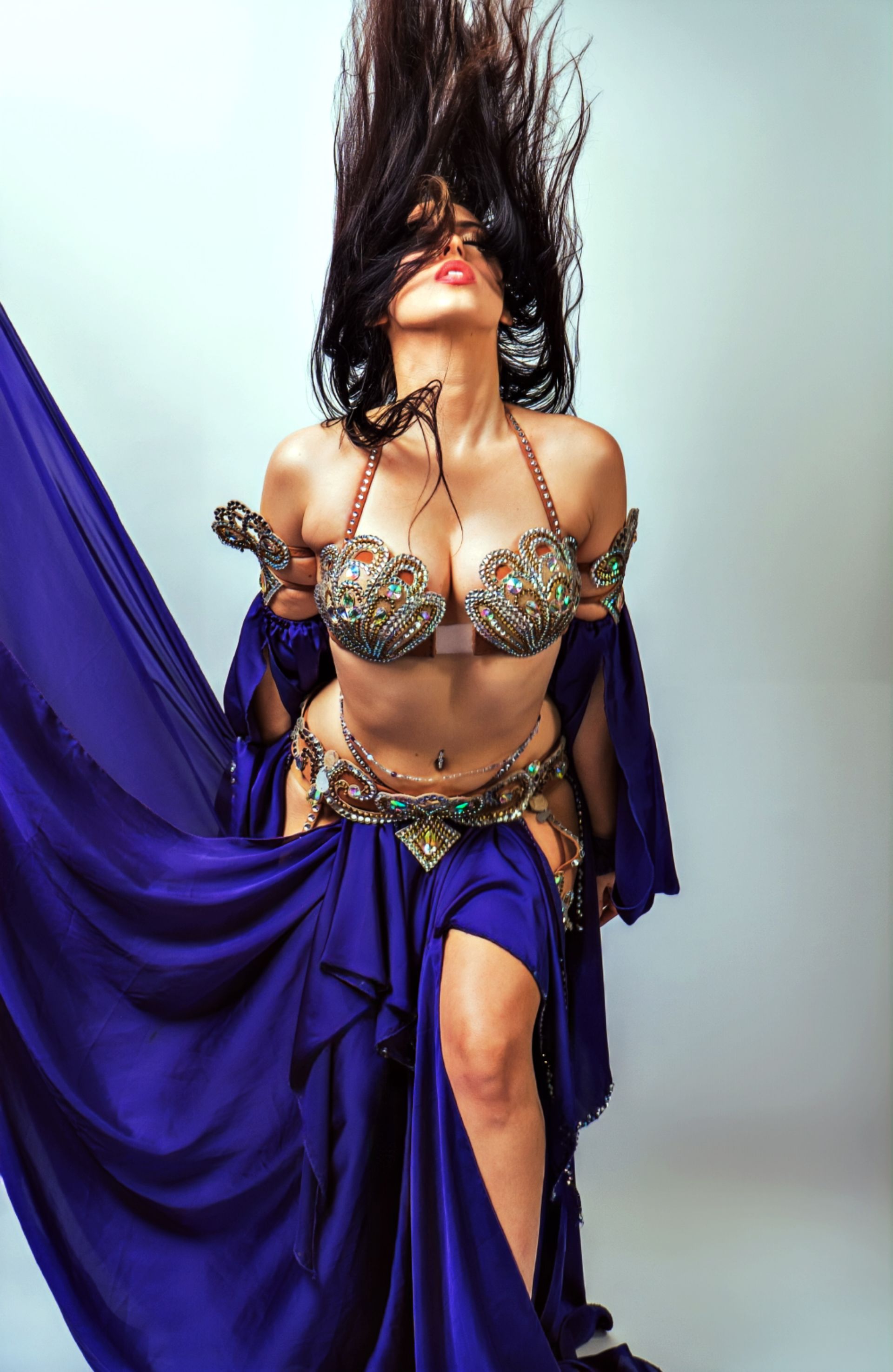 Belly dancer Azeeria Azizah in a blue dress is dancing with her hair blowing in the wind.