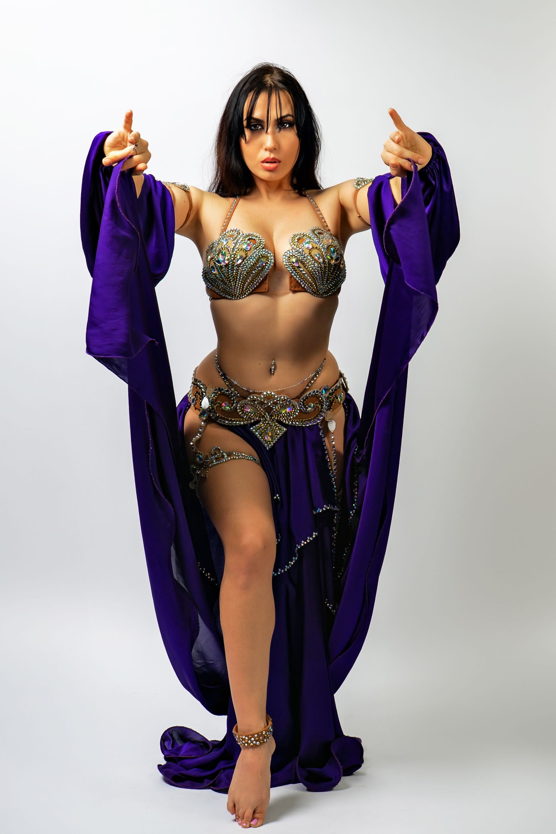 Belly dancer Azeeria Azizah in a purple dress is giving a thumbs up.