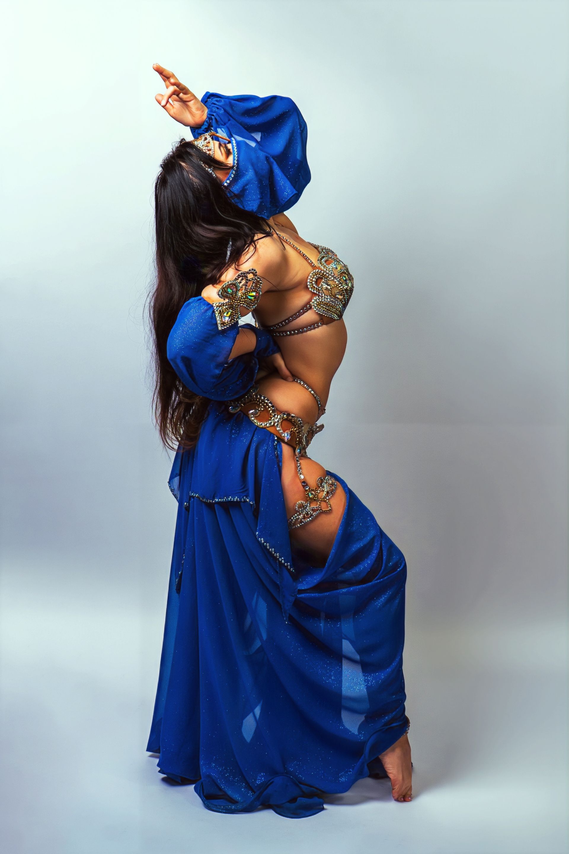 Belly dancer Azeeria Azizah in a blue dress is dancing on a white background.