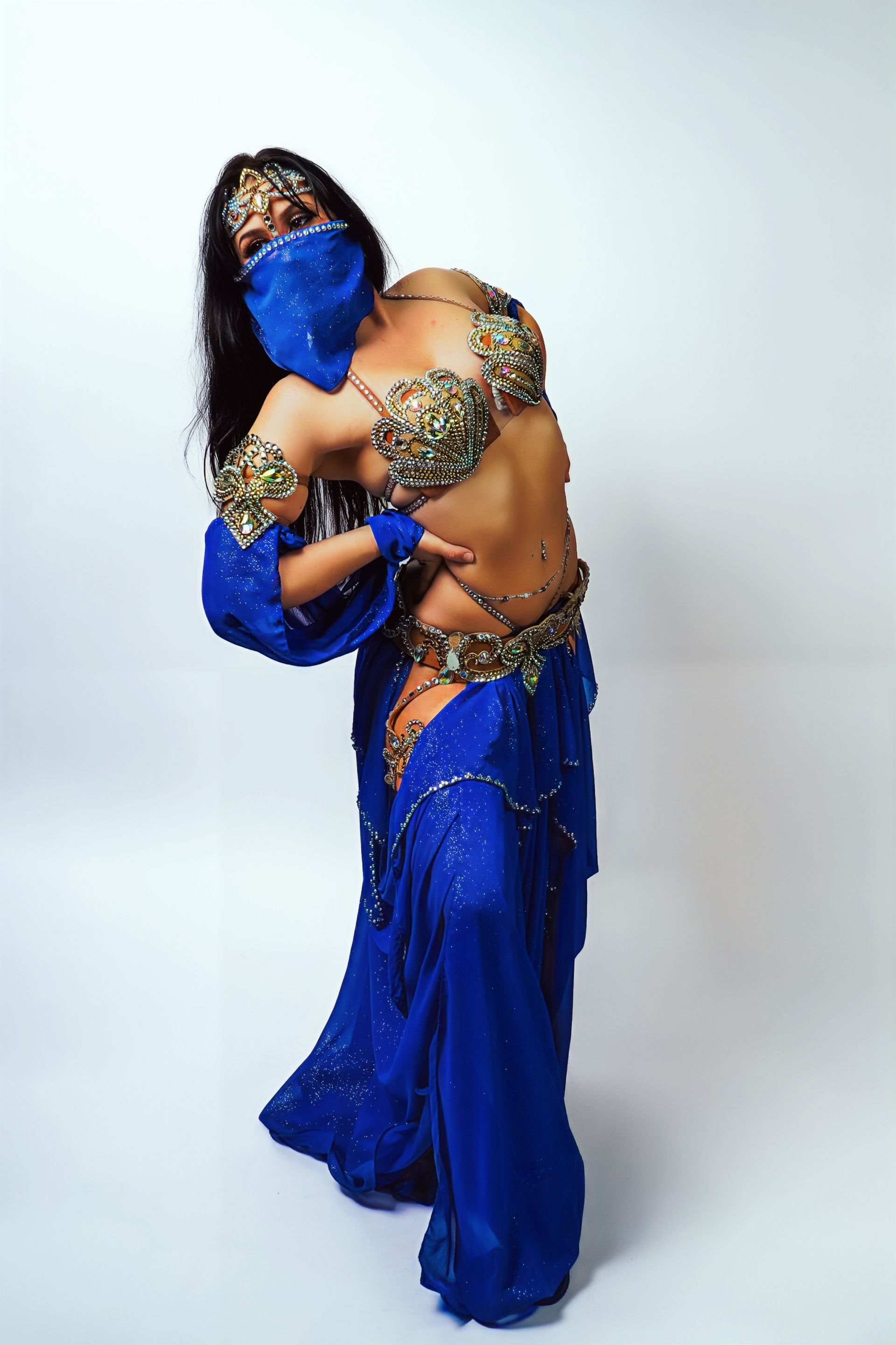 Belly dancer Azeeria Azizah is wearing a blue dress and a mask.