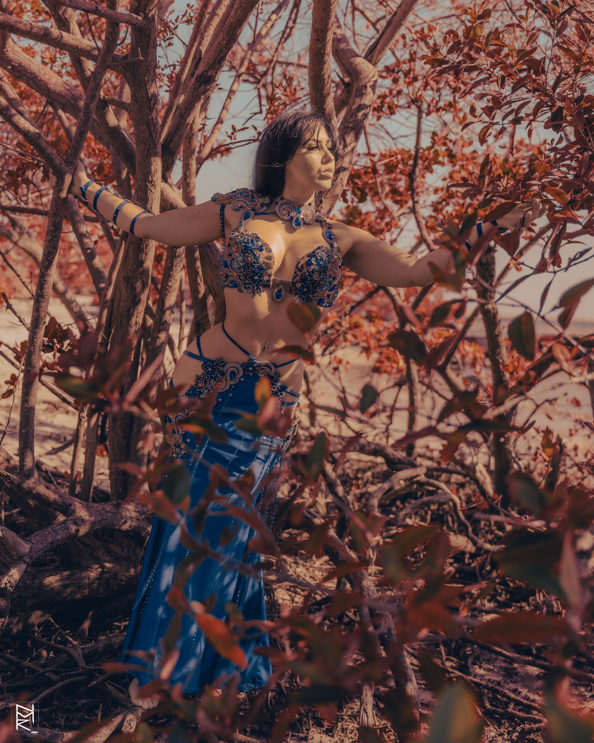 Azeeria Azizah in a blue dress posing in the woods.
