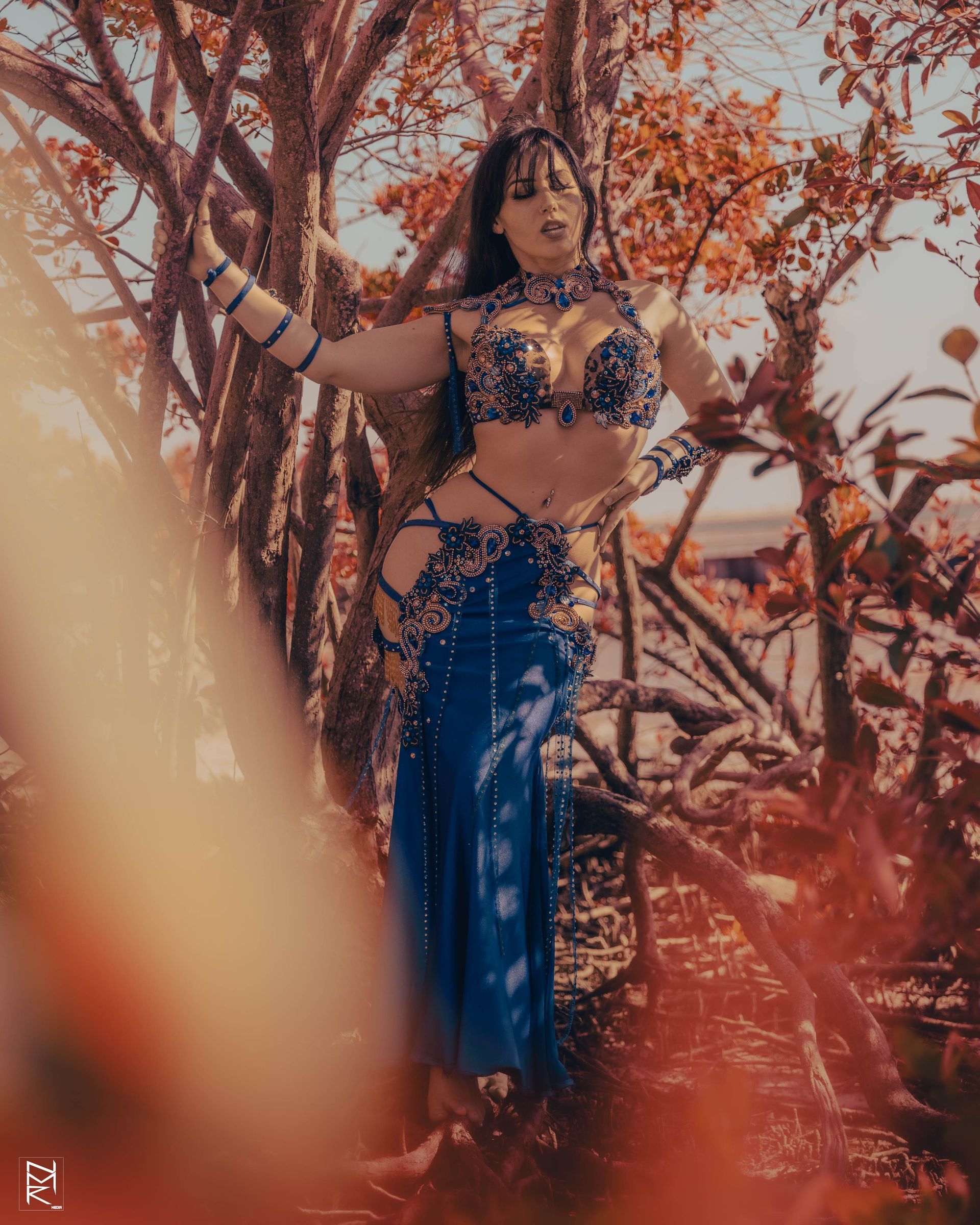 Azeeria Azizah in a belly dancer costume standing in the woods.