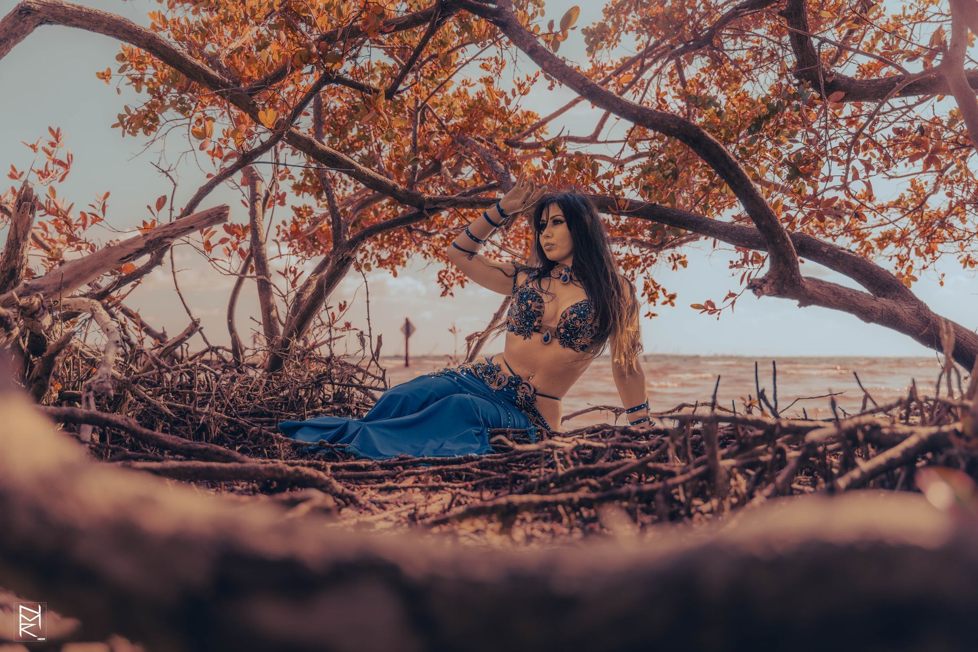 Azeeria Azizah is sitting under a tree on the beach.