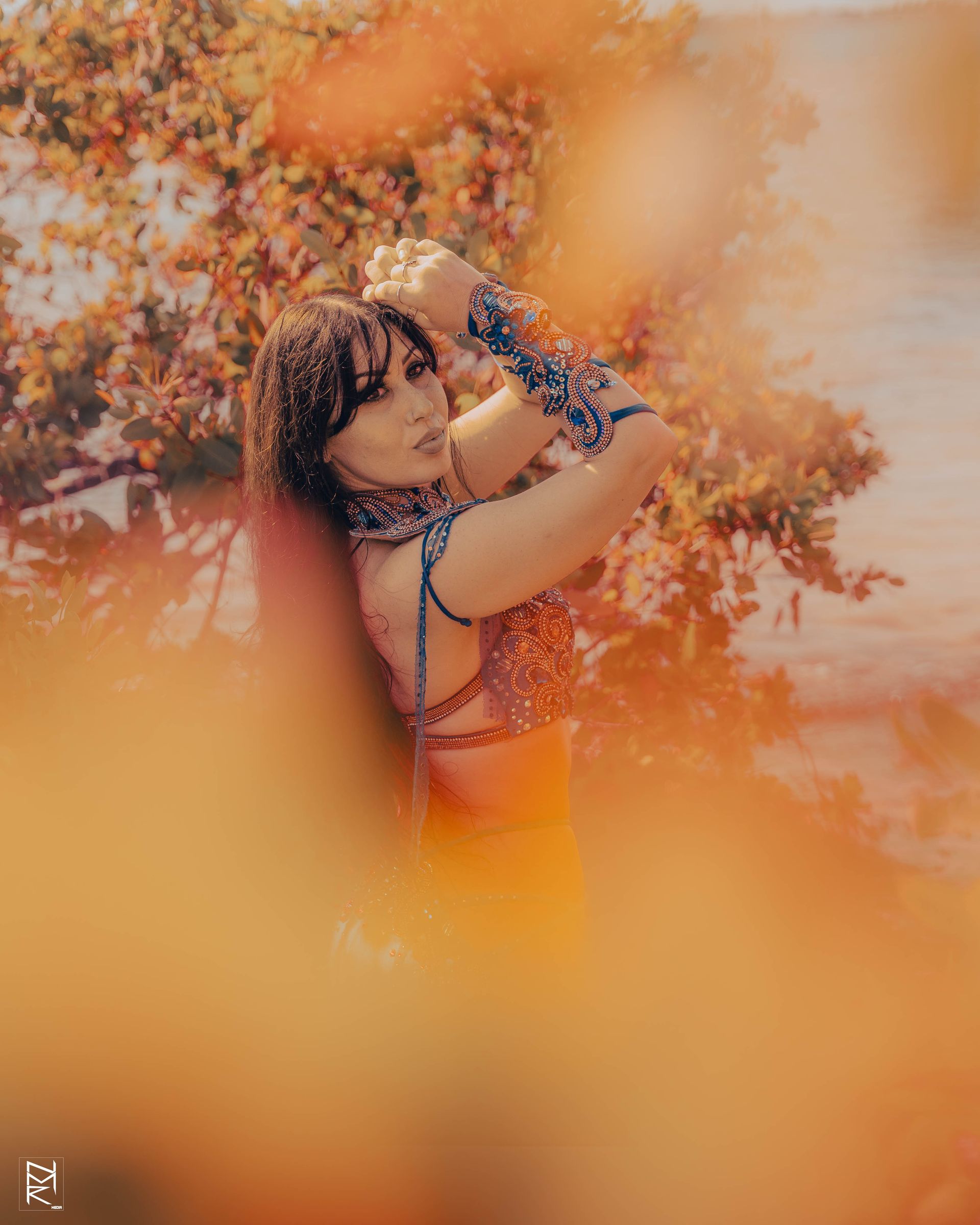 Azeeria Azizah in a dress is standing in front of a tree posing for the camera.