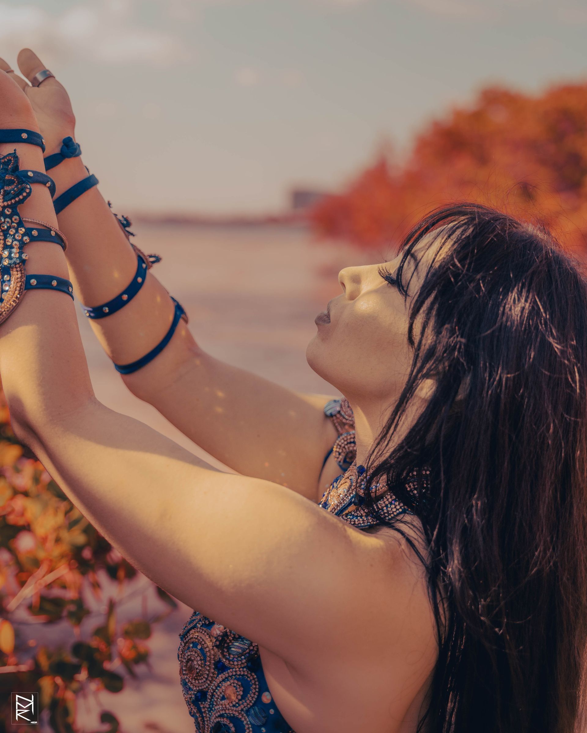 A photo of Azeeria with her hands in the air reaching for a tree branch.