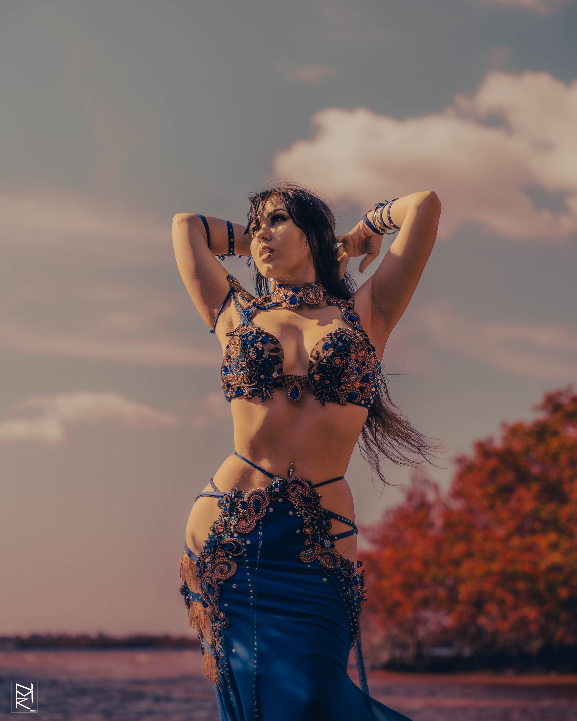 A photo of the Belly Dancer Azeeria Azizah posing in the water with her hands above her head at cypress beach, Tampa Fl