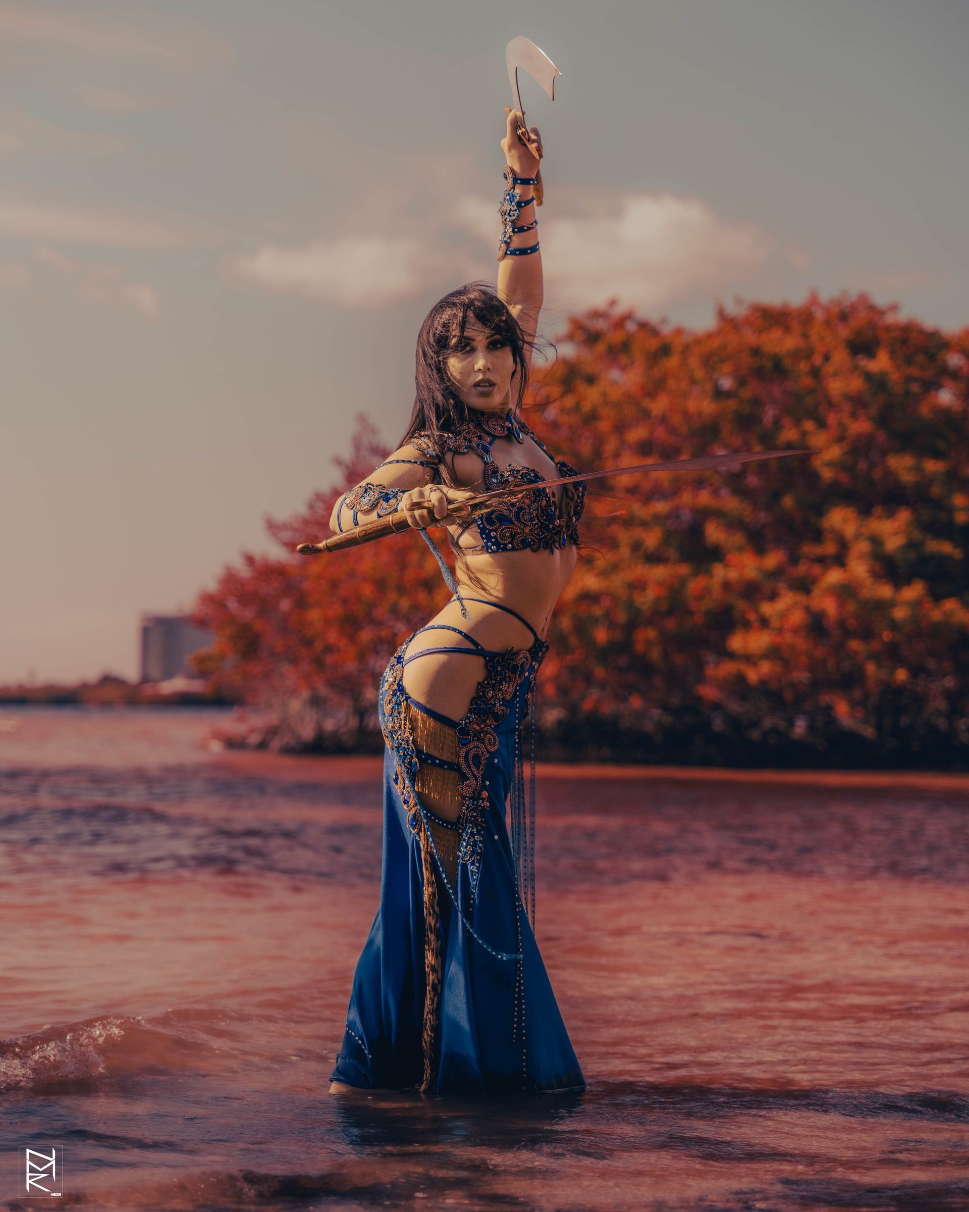 A photoshoot of the Belly Dancer Azeeria Azizah as she poses with two swords in the water at cypress beach, Tampa Fl